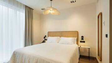 Habitación de hotel con una cama grande, una mesita de noche con lámpara, teléfono en la pared y un espejo.