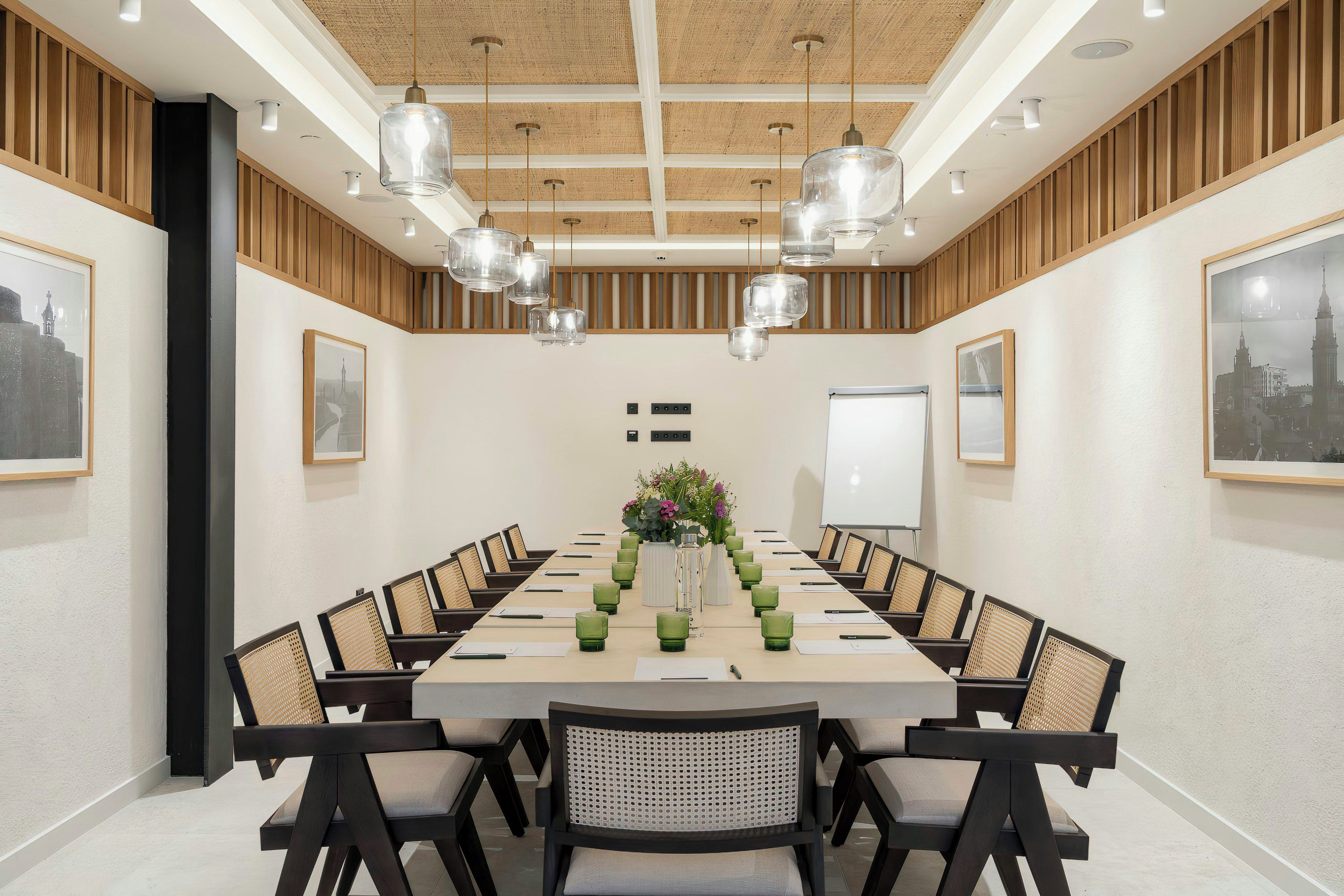 Un salón de conferencias con una larga mesa, sillas, una pizarra y cuadros en las paredes.