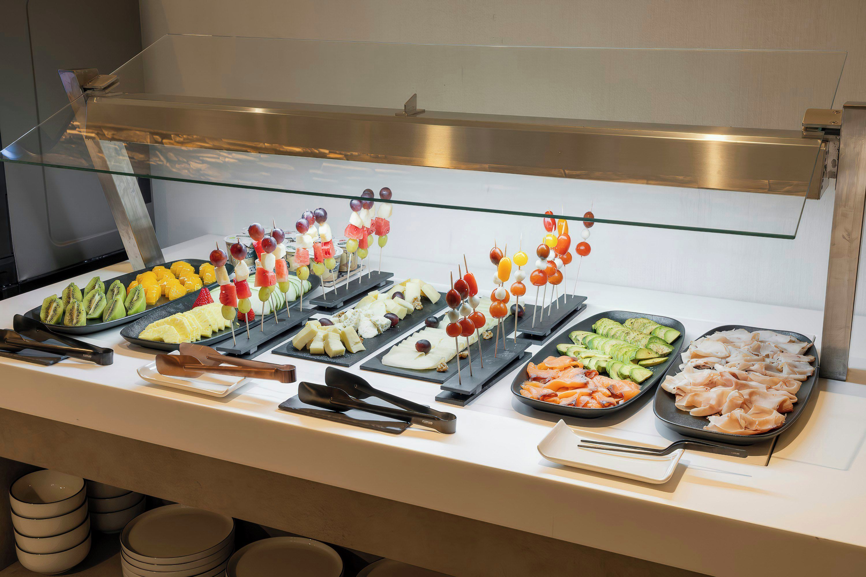 A buffet with various food items including fruits, cheeses, and meats.