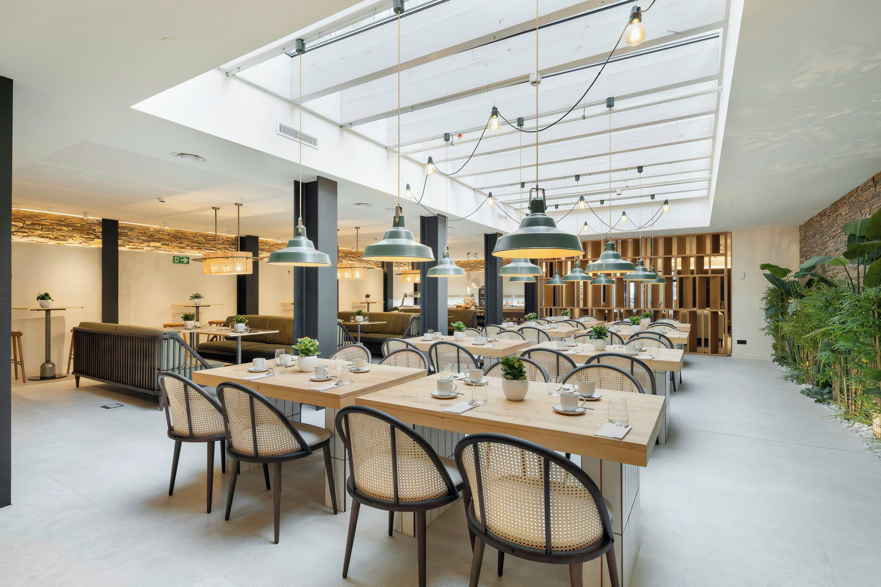 A modern dining area with high ceilings, pendant lighting, and a central seating arrangement.