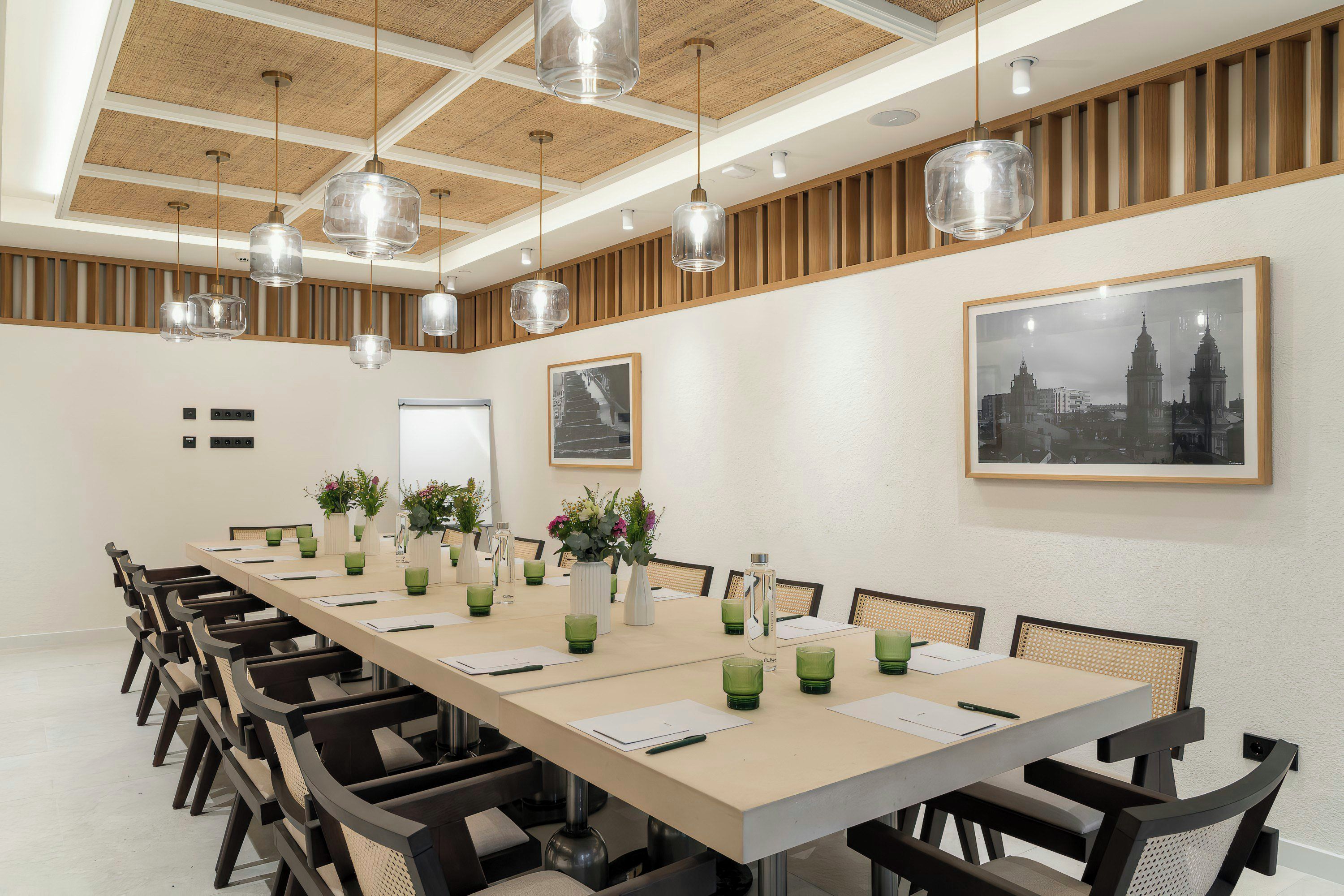 A conference room with a long table, chairs, and hanging pendant lights.