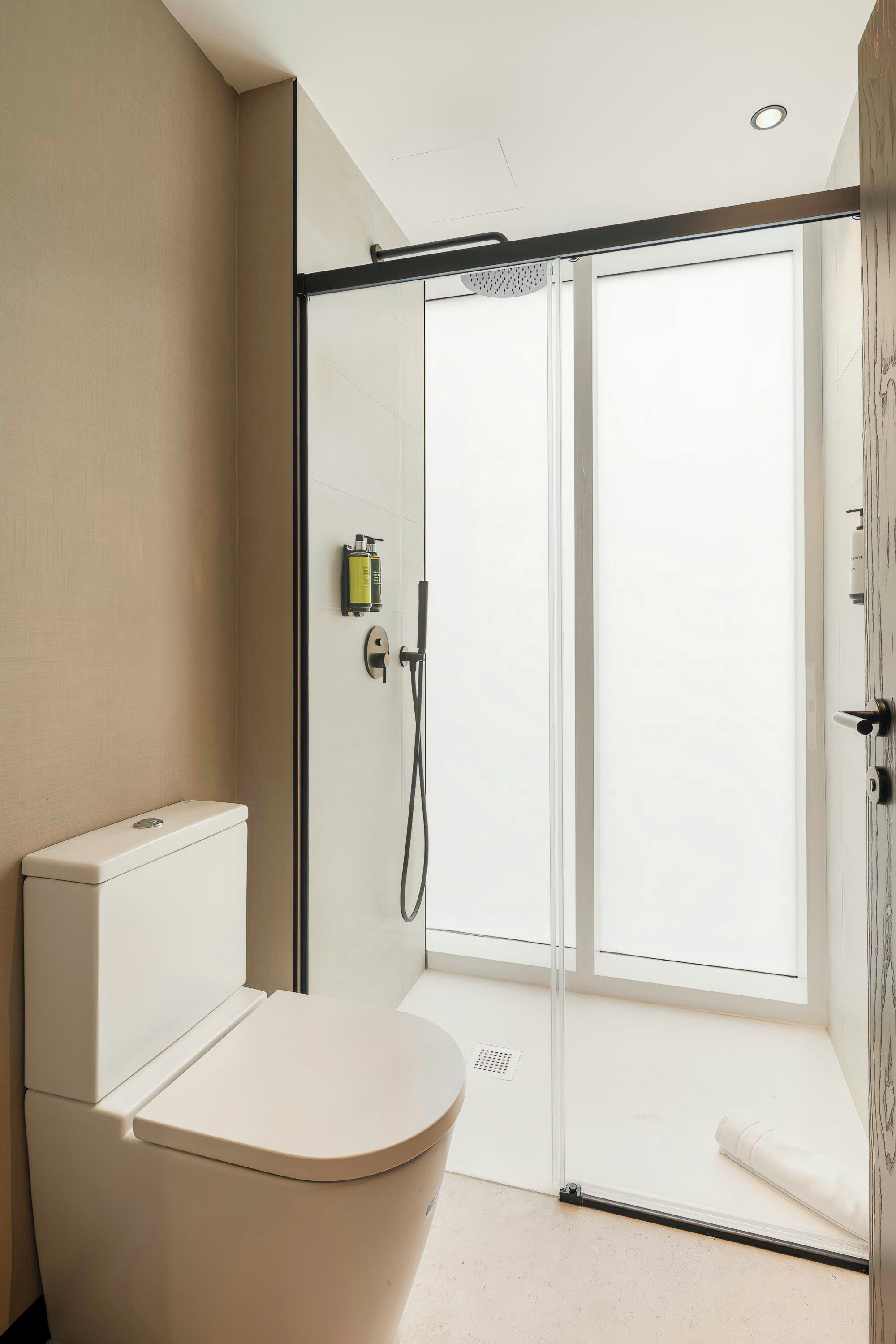 Un baño moderno con inodoro, ducha y puerta de cristal que da a un balcón.