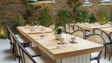 Un restaurant doté de nombreuses tables, de chaises et de luminaires suspendus.