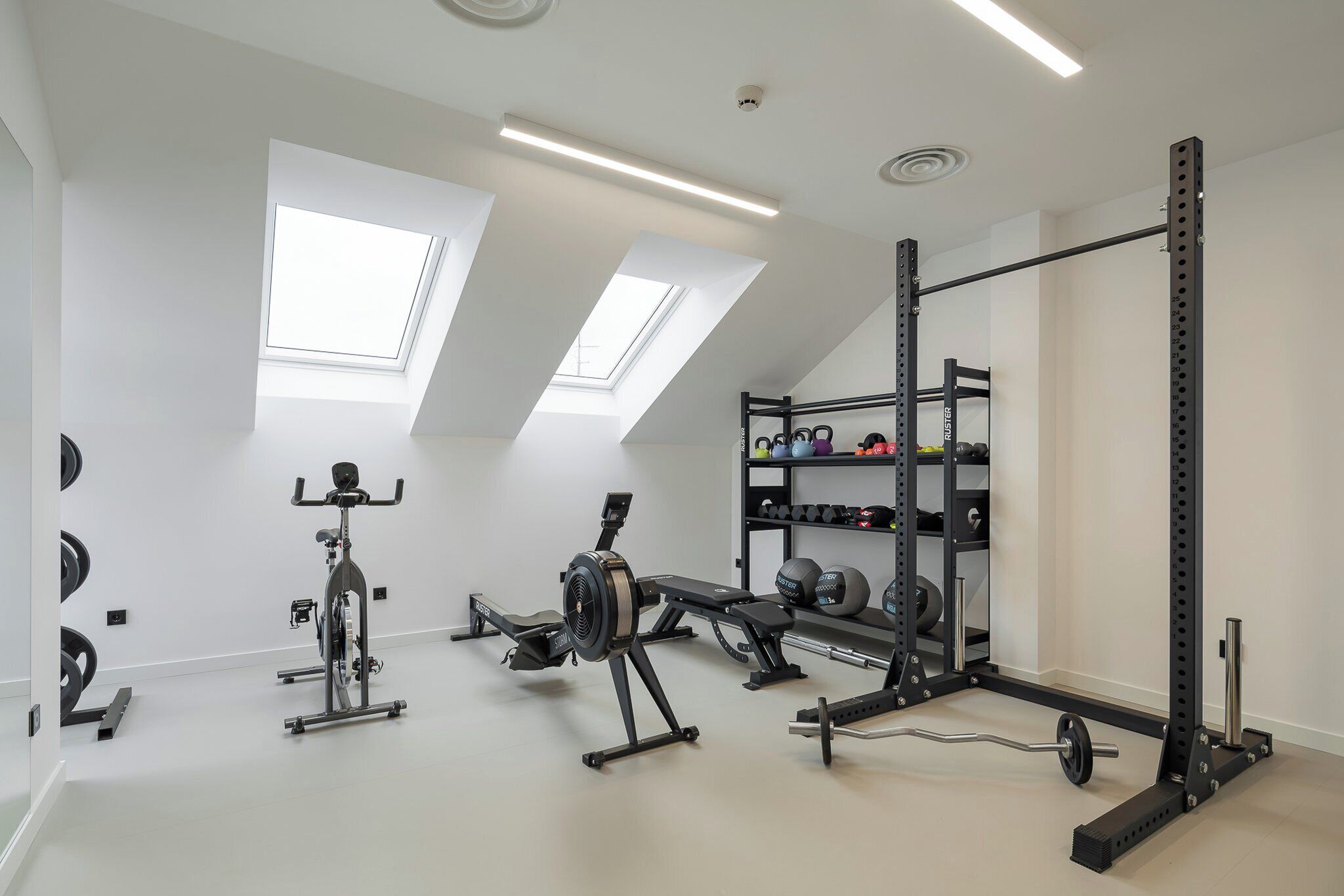 Un gimnasio con ventiladores de techo, equipo de ejercicio y un rack para pesas.