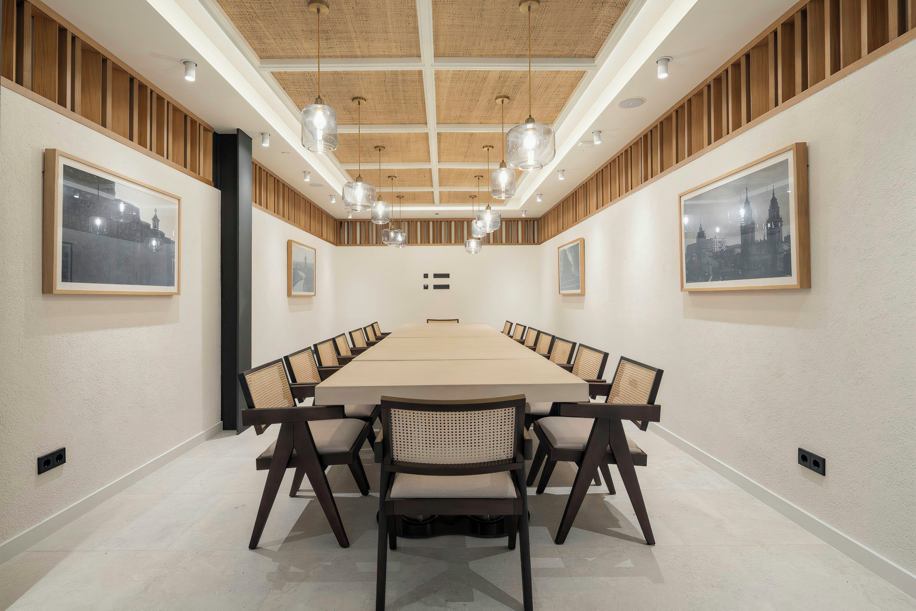 Una sala de conferències amb una taula llarga, cadires i il·luminació penjant.