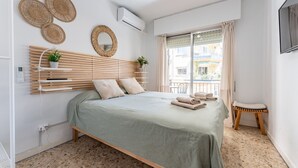 Um quarto moderno com cama, cabeceira de madeira, uma mesa pequena e janela com cortinas.