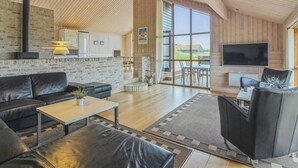 A spacious living room with a fireplace, a TV, and a large window offering a view of the outdoors.
