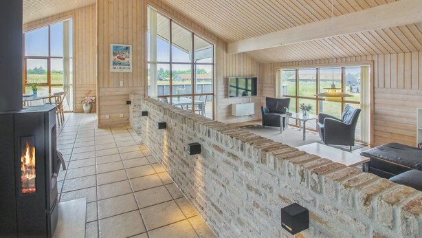A spacious living area with a fireplace, large windows, and a stone wall.