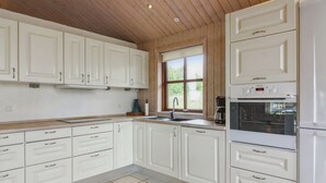 A modern kitchen with white cabinets, a built-in oven, and a window providing natural light.