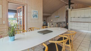 A wooden interior with a dining table, chairs, a kitchen area, and a fireplace.