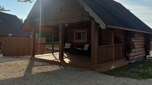 A log cabin with a porch, a small dining area, and a number '3' on the wall.