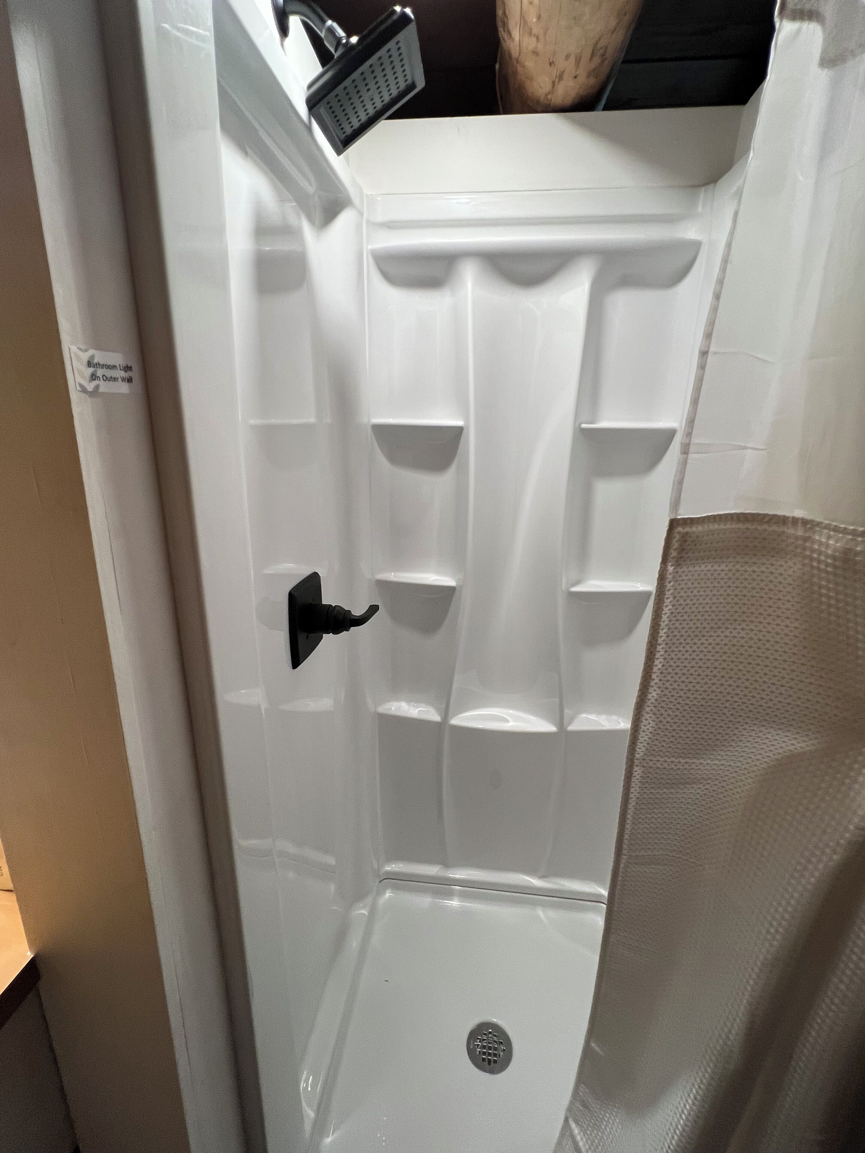 Baño con box de ducha blanco, desagüe visible y toallero.