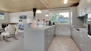 Une cuisine moderne avec des meubles de couleur grise, un îlot central et un plafond en bois.