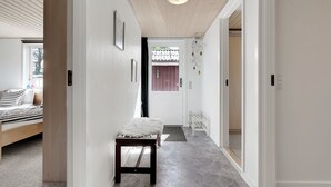 Un couloir avec un lit, un banc et une porte donnant sur une autre pièce.