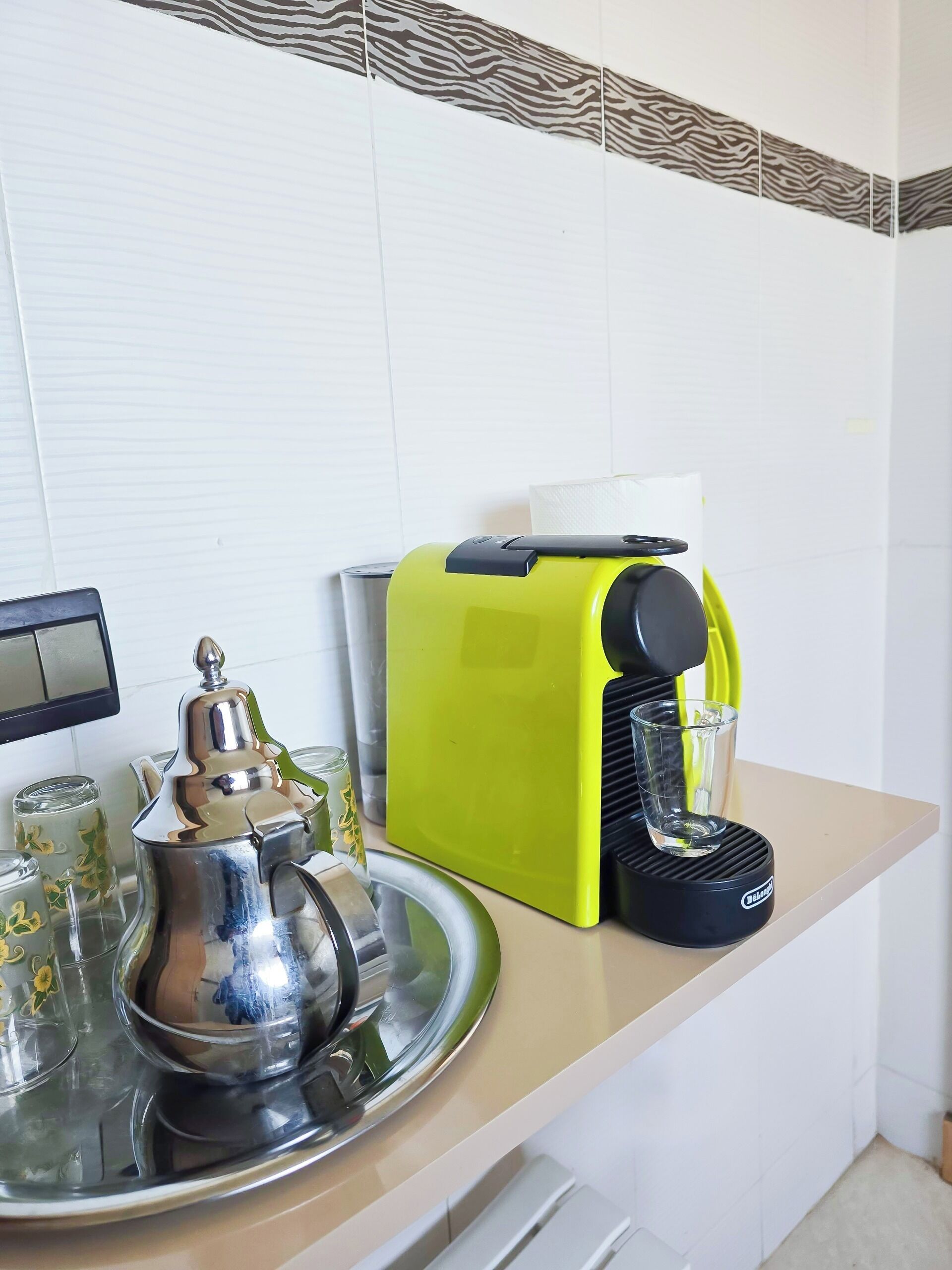 Uma bancada de cozinha com uma cafeteira, um tabuleiro com um bule e um copo.