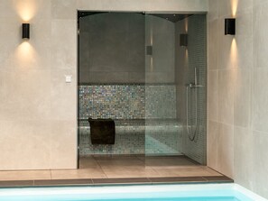 A glass-enclosed shower with a tiled mosaic wall, a towel hanging on the door, and a pool adjacent to the shower. - "Lilie" - 270m from the sea by Interhome (Hals)