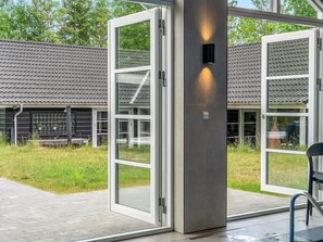 A modern building with large glass doors, a concrete pillar, and a tiled roof.