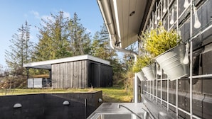 Une cuisine extérieure moderne dotée d’un évier en acier inoxydable et d’une terrasse en bois.