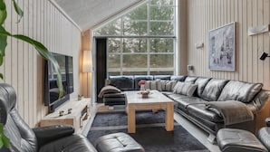 Un salon moderne doté d’une grande fenêtre, de canapés en cuir, d’une table basse et d’un téléviseur à écran plat.