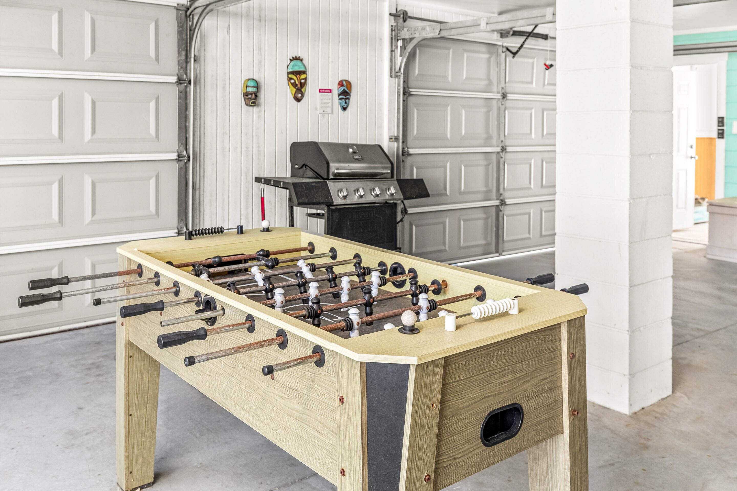 Ett fotbollsspel i ett garage, med en grill och dekorativa masker på väggen.