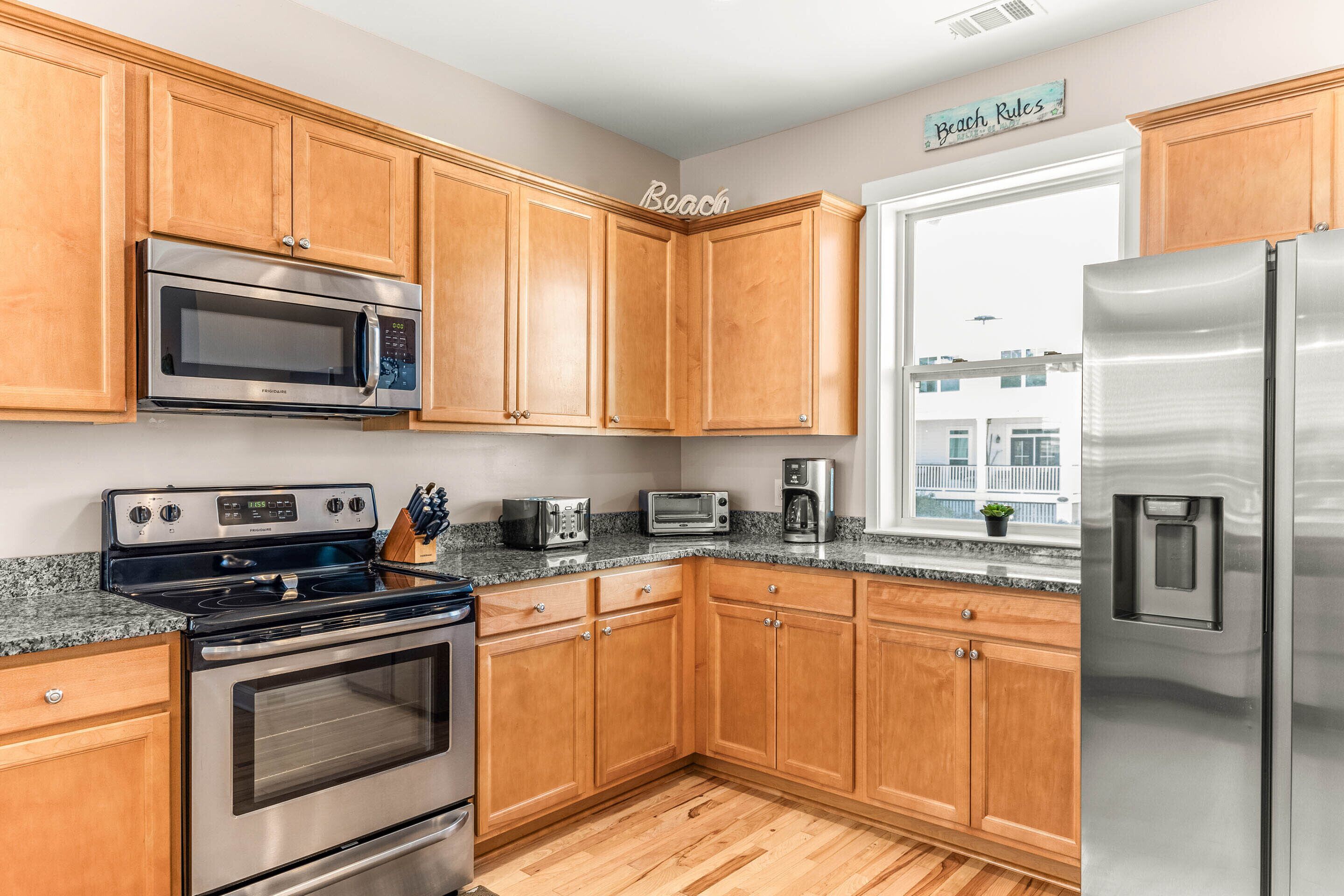 A kitchen with wooden cabinets, stainless steel appliances, and a window with a view of buildings.