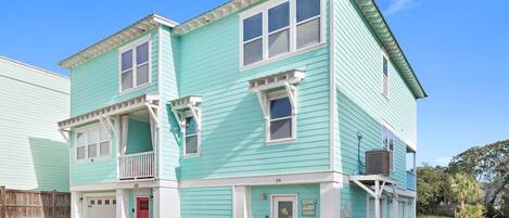 A two-story building with a light blue exterior, white trim, and a red door.