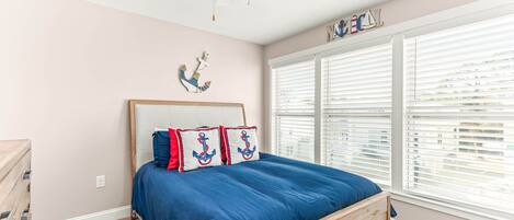 Un dormitorio con una cama de madera, un ventilador de techo y una ventana con persianas.