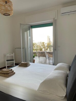 A bedroom with a bed, a chair, a small table, and a view of an outdoor balcony. - Monopoli Roof - Penthouse with sea view and terrace (Monopoli)