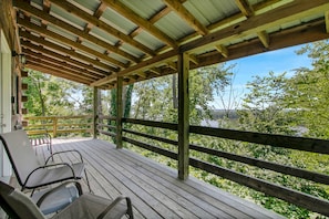 Eine überdachte Terrasse mit Holzwerteln und Metallstühlen.