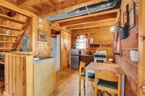 Ein Holzblockhaus-Interieur mit Küche, Essbereich und einem kleinen Badezimmer.