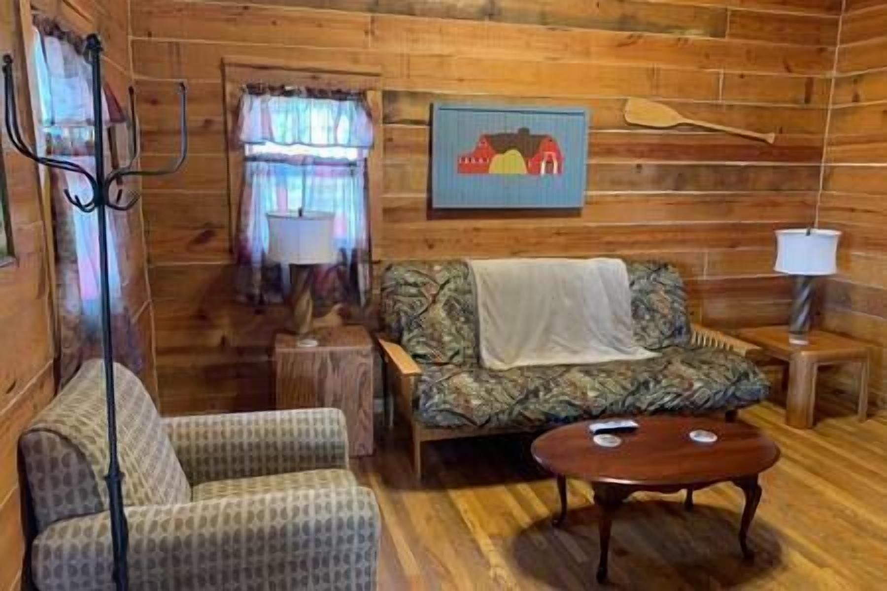 Ein gemütliches Cabin-Interieur mit einem gemusterten Sofa, einem Holztisch, einer Lampe und einem Bild an der Wand.