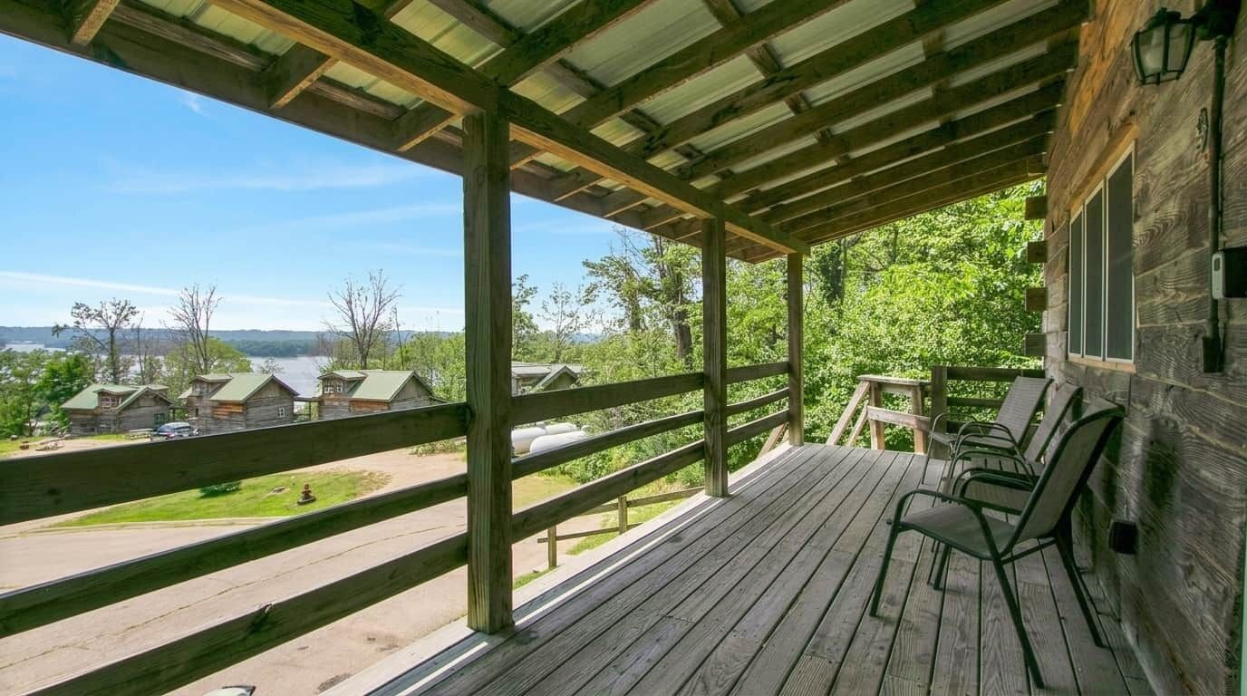 A wooden deck with a view of cabins and a lake.