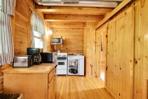 Una cocina de madera funcional con microondas, tostadora y estufa.