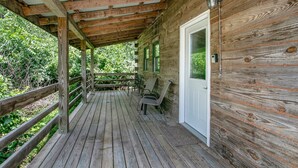 Une terrasse en bois avec un porche couvert, une porte et une fenêtre.