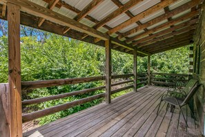 A wooden deck with a metal roof, surrounded by lush greenery.