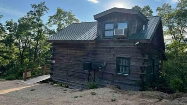 Une cabane rustique avec un toit en pente, un petit porche et une fenêtre.