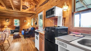 Interior de una cabaña de madera con cocina, comedor y sala de estar.