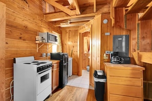 A compact kitchen with a stove, microwave, refrigerator, and coffee maker.