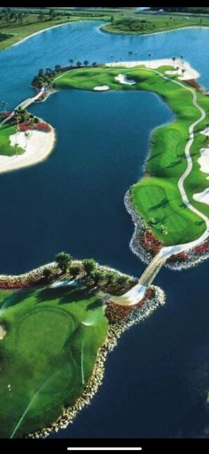 Vista aérea de un campo de golf con varias zonas verdes y cuerpos de agua.