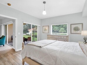 Relax in this serene bedroom with a large bed, window, and sliding glass door leading to an outdoor area.