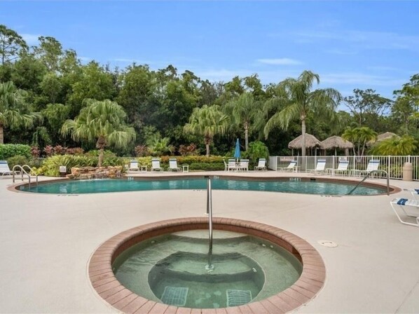 Relax by the oval-shaped pool surrounded by lush greenery and lounge chairs.