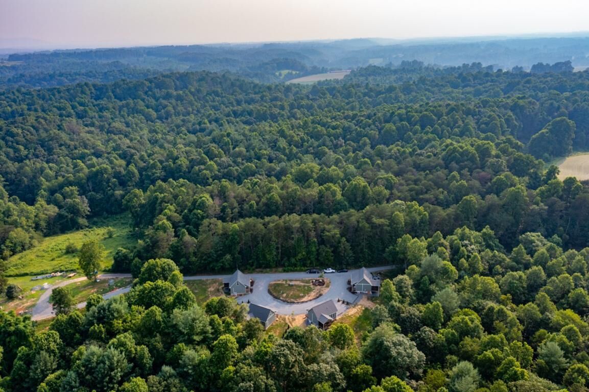 An aerial view of a forested area with a circular driveway and several buildings.