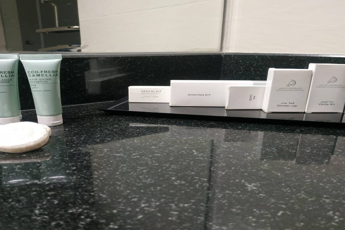 A bathroom counter with toiletries including a facial cleanser, shampoo, and various personal care items.