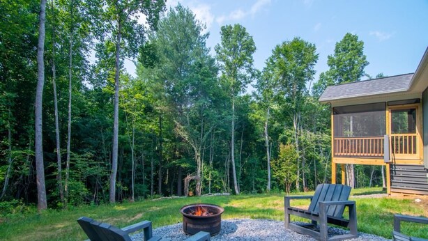 Una cabaña con terraza, fogata y sillas Adirondack.