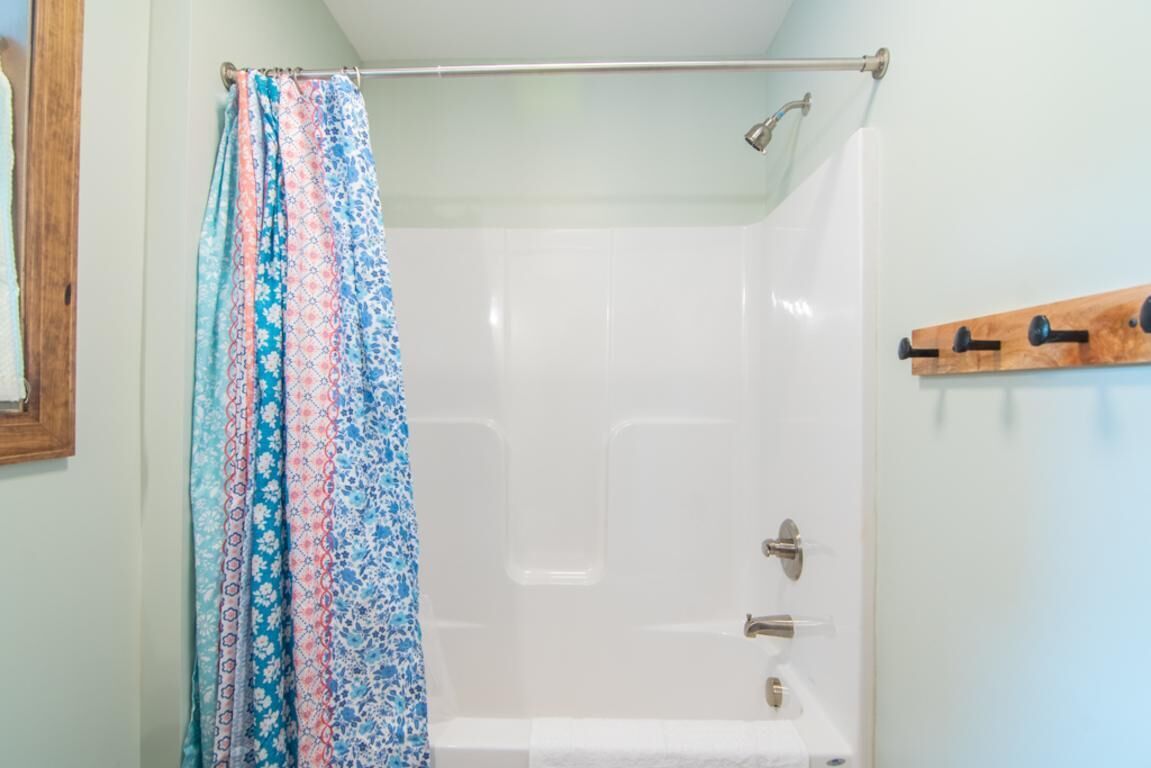 A shower with a metal rod and a wooden rack.