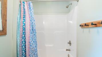A shower with a metal rod and a wooden rack.