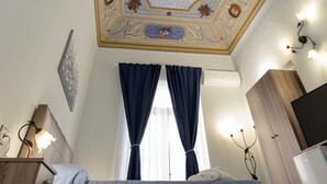 A bedroom with a bed, a nightstand, a dresser, a television, and a ceiling with decorative moldings. - Catania Center B&B (Catania)