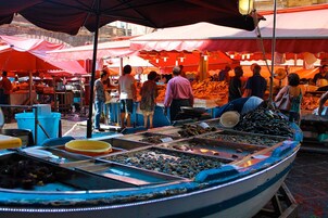 Puesto de mercado con mariscos exhibidos en bandejas.