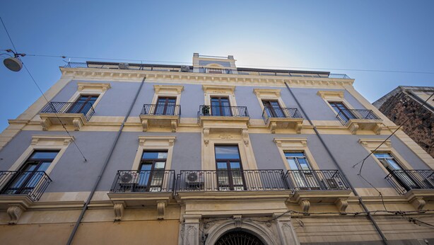 A multi-story building with a symmetrical facade, multiple balconies, and a central entrance with an arched doorway. - Catania Center B&B (Catania)