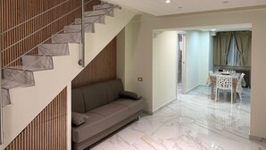 A modern interior with a staircase, a sofa, a dining area with a table and chairs, and a kitchen visible through an open door. - Catania Center B&B (Catania)